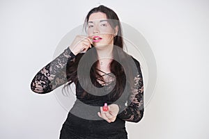 Asian happy woman paints her lips with lipstick on white studio background. Wrong try to do good self make up. Adult girl is learn
