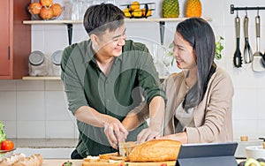 Asian happy young adult couple lover helping together for cooking in cozy home kitchen in morning, preparing meal, making salad,