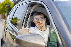 Asian happy young handsome man driving a car in front seat with smile prepare to journey with his car