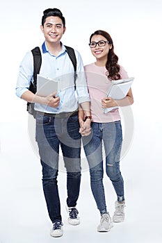 Asian happy young student couple walking with books in hands, isolated on white background