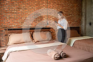 Asian head housekeeper checks the cleanliness in hotel room