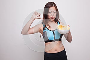 Asian healthy girl thumbs down with potato chips.