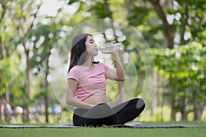Asian healthy pregnant woman relaxing in the garden and drinking water