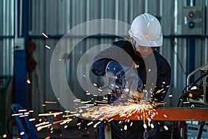 Asian heavy industry workers factory interior with industrial worker using angle grinder and cutting a steel