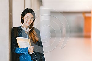 Asian high school girl or college student wearing eyeglasses, smiling in university campus with copy space. Education concept