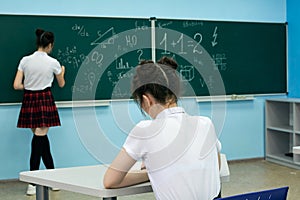 asian high school girl solves geometry on the blackboard