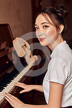 asian high school student sitting at the piano