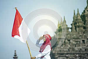 Asian Hijab Holding Indonesian flag with clear blue skyand Plaosan Temple background, Indonesia independence day