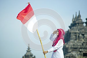 Asian Hijab Holding Indonesian flag with clear blue skyand Plaosan Temple background, Indonesia independence day