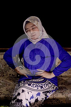 Asian hijab woman ,with painfully expression . Holding her stomach .