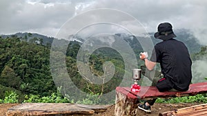 asian hiker man relax and happy feeling drink coffee and see to mountain view