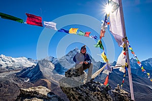 Asian hiker sitting on the cliff in Nangkartsang Peak, Everest Base Camp, with himalayan mountain range at the background