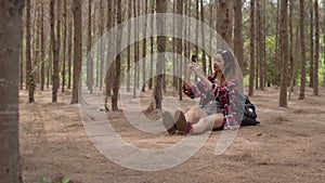 Asian hiker woman trekking in forest. Young happy backpack girl using phone take pictures photo while travel nature and adventure