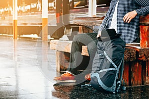 Asian hipster young man sitting at train station with awaiting t