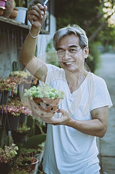 asian holding hanging houseplant pot toothy smiling with happiness face standing outdoor