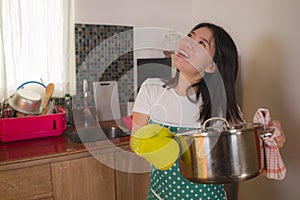 Asian home cook girl lifestyle portrait . Young happy and beautiful Korean woman in kitchen apron and glove holding cooking pot