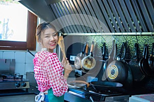 Asian home cook woman holding spatula with both hands cooking in the kitchen, Healthy Food, Healthy Lifestyle, Seasoning