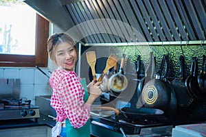 Asian home cook woman holding spatula with both hands cooking in the kitchen and looking to the camera, Healthy Food.