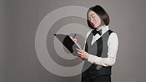 Asian hotel concierge creating a checklist of registrations
