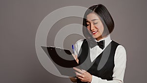 Asian hotel concierge creating a checklist of registrations