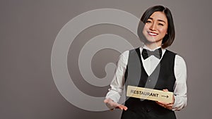 Asian hotel concierge holding restaurant sign to indicate direction