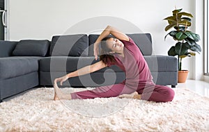 Asian housewife practicing yoga and doing revolved head to knee forward exercise during home workout, female sitting in Parivrtta