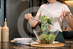 Asian housewife preparing fresh vegetables to make salad at home kitchen counter