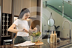 Asian housewife preparing fresh vegetables to make salad at home kitchen counter