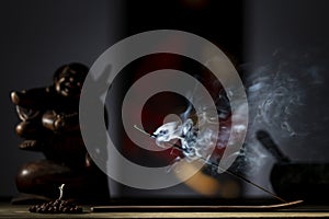 Asian incense stick in stick holder burning with smoke on dark background, closeup. Meditation, yoga, self development and sound