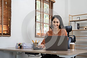 Asian indian Female director working in the office sitting at a desk analyzing business statistics holding diagrams and