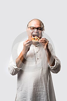 Asian Indian old man eating pizza with funny expressions