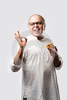 Asian Indian old man eating pizza with funny expressions