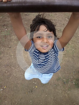 Asian Indian todder boy hanging swing having fun