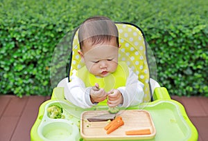 Asian infant baby boy eating by Baby Led Weaning BLW. Finger foods concept