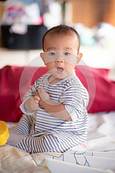 Asian infant baby sitting and playin on the bed after wake up in the morning