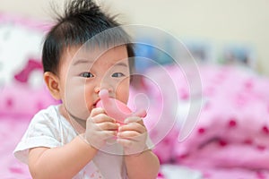 Asian Infant girl biting teether, baby growing first tooth