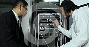 Asian Internet technician checking modem cabinet.