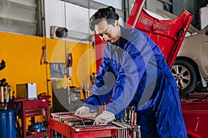 Asian Japanese male mechanic worker portrait in auto service workshop car maintenance center replace fix auto engine part