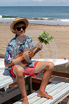 Asian, Japanese teenager playing the Ukulele on a beach in Chiba Japan