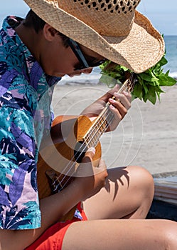 Asian, Japanese teenager playing the Ukulele on a beach in Chiba Japan