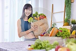 Asian Japanese woman holding shopping bag from supermarket full of organics vegetables and fruits for healthy food and vegetarian