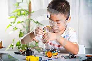 Asian kid boy assembling the Arduino robot car homework project at home photo