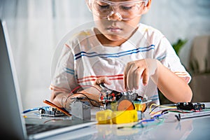 Asian kid boy assembling the Arduino robot car homework project at home photo