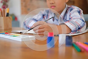 asian kid boy child schoolboy holding paint brush drawing painting watercolor. children leisure activity at home