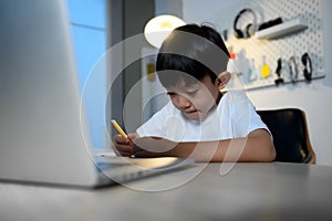 Asian Kid Boy Focused on Homework and Learning Alone in Room at Home, Serious Asian Kid Concentrating on Homework, Studying and