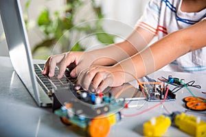 Asian kid boy learns coding and programming with laptop for Arduino robot car