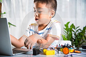 Asian kid boy learns coding and programming with laptop for Arduino robot car