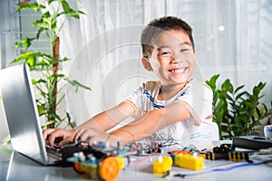 Asian kid boy learns coding and programming with laptop for Arduino robot car