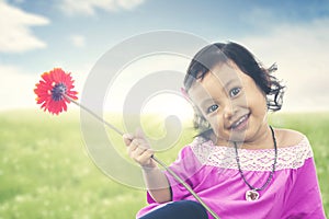 Asian kid brings garbera flower on meadow with sunlight. Summer or spring concept.