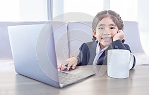 Asian kid in business use laptop with hot ceremic mug photo
